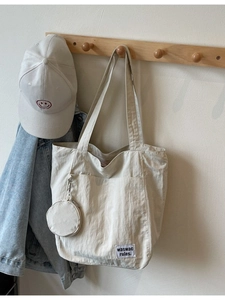 Minimalist off-white canvas tote bag and baseball cap set hanging on wooden hook