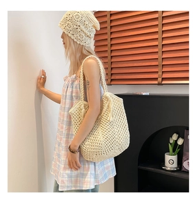 Close-up of beige crochet tote bag with fringe and matching floral knit sun hat