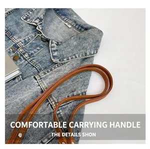 Close-up of brown leather handles with rivets on a blue denim woven handbag