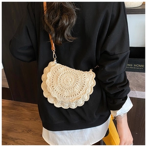 Detail of hand-woven cream crochet saddle bag with brown strap and petal-edged texture