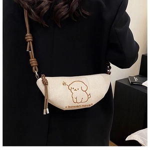 Détail du sac bandoulière en toile beige avec broderie chien et sangle à nœud élégante