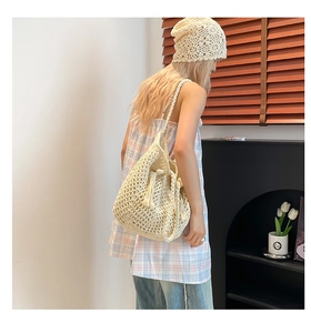 Detail of cream-white crochet tote with fringe tassel and openwork mesh texture