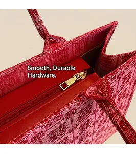 Close-up of red jacquard tote bag with geometric embroidery and gold zipper detail