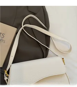 Detail of white lychee leather texture and golden hardware on a shoulder bag strap
