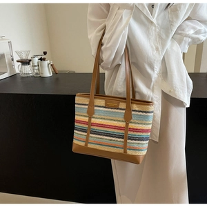 Detail of colorful striped woven tote bag with brown leather trim and retro logo patch
