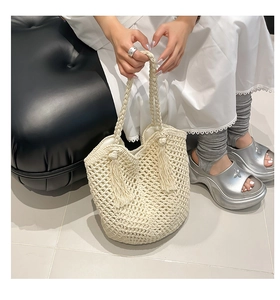 Detail of cream woven tote bag featuring hollow mesh texture and stylish long tassels
