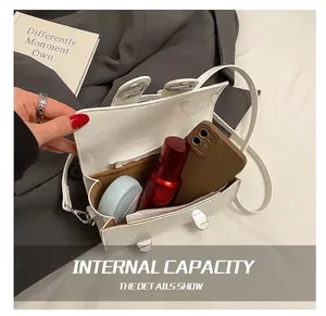 Detailed interior of a white patent leather bag showing space for cosmetics and smartphone