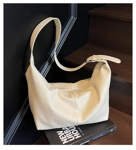 Detail of off-white lychee grain leather hobo bag with adjustable strap and silver buckle