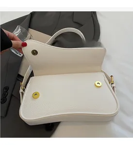 Detail of white lychee leather shoulder bag with gold magnetic buckle on grey suit