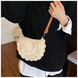 Detail of bohemian knit saddle bag with scalloped edges and brown leather strap