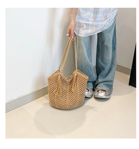 Detailed close-up of handmade hollow woven texture and tassels on straw tote bag
