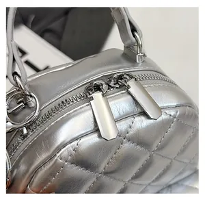 Detail of a smooth silver quilted backpack featuring high-quality dual metal zippers