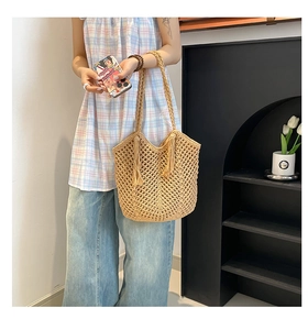 Close-up of bohemian woven straw tote bag with intricate hollow mesh and side fringe tassels