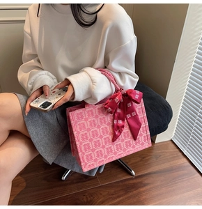 Close-up of pink woven wedding tote bag with Xi character patterns and a red satin bow