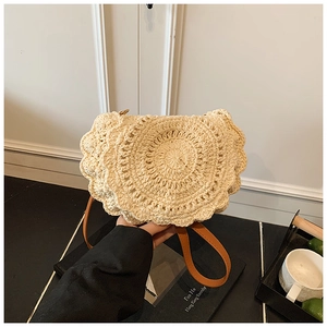 Close-up of beige woven shoulder bag with unique scalloped edges and brown leather strap