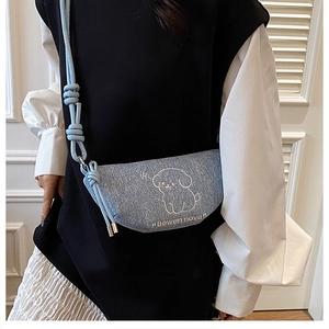 Détail du sac demi-lune en denim bleu clair avec broderie de chiot blanc et bandoulière fine
