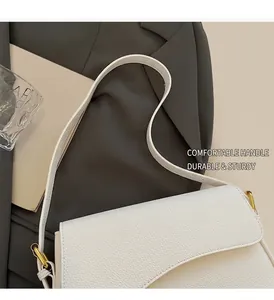 Detail of white lychee leather texture and golden metal buckle on a chic shoulder bag