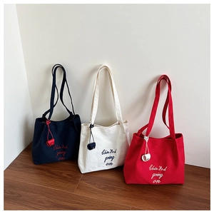Détail de sacs cabas en toile noir, blanc et rouge avec broderie et petites pochettes assorties