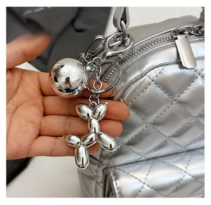 Detailed close-up of a silver metallic balloon dog charm on a quilted backpack