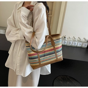 Detail showing colorful striped woven texture and brown leather handles on summer tote bag