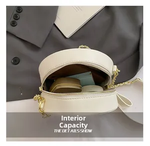 Internal view of a circular white crossbody bag with cosmetics and a metal chain strap