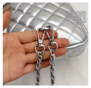 Detail of silver metallic quilted bag featuring a removable chain shoulder strap and clasp