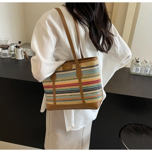 Detail of colorful striped woven straw tote bag with brown leather handles in a cafe