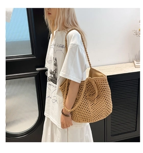 Detail of hollow woven beige straw tote bag showing intricate texture and thick shoulder strap