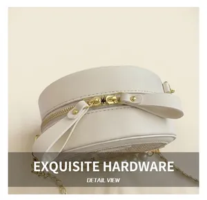 Detail of white round chain bag showing golden zippers and elegant pearl decorations