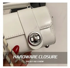 Detail view of the silver circular twist lock on a white patent leather pillow bag