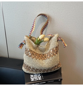 Detail of hollow star pattern and colorful woven strap on a beige straw tote bag
