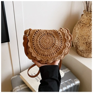 Detail of hand-woven straw saddle bag with scalloped edges and brown leather strap