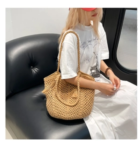 Detail of hand-woven straw tote bag with textured knit pattern and tassel accessory