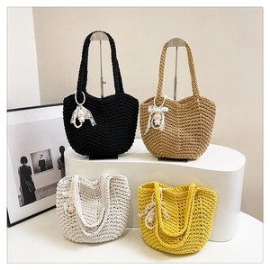 Woven tote bags in four colors with lace bows and cute pendants on a display stand