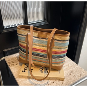 Detail of colorful woven tote bag with leather straps and patch on marble and book