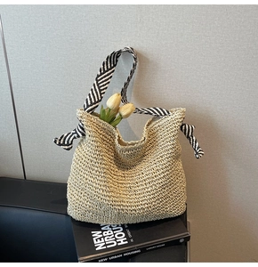 Detail of woven straw tote bag with black and white striped ribbon handle and tulip decor
