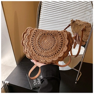 Detailed view of handmade brown straw saddle bag with decorative wavy scalloped edges