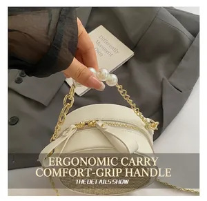 Detail of round beige crossbody bag with pearl handle, woven texture and dual zippers