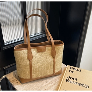Detail of rainbow straw woven tote with brown leather trim and fashion label on table