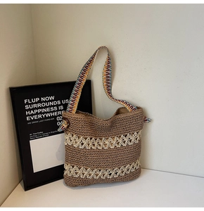 Detail of woven straw tote bag featuring white hollow floral patterns and colorful bohemian strap