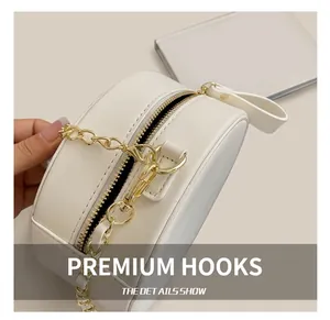 Detailed close-up of the bright golden metal zipper and chain clasp on white round bag