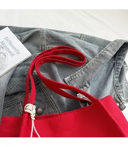 Détail du grand sac cabas en toile rouge avec larges bretelles et nœud en corde blanche