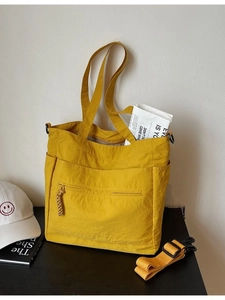 Ginger yellow large tote bag with adjustable shoulder strap on a black wooden surface