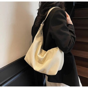Close-up of pebble-textured hobo bag on model, featuring spacious off-white leather design