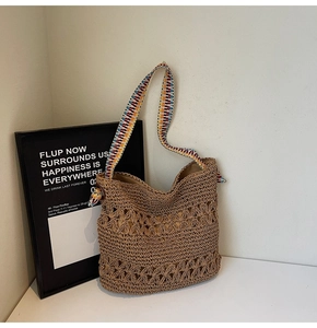 Detail of woven straw tote bag featuring a colorful ethnic style knit shoulder strap