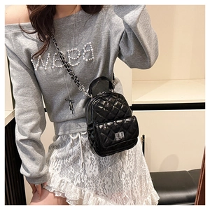 Detail of black quilted mini backpack featuring chain straps and a classic turn-lock pocket