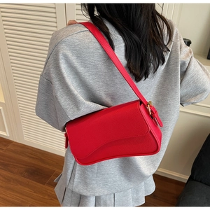 Detail of red pebbled leather shoulder bag with gold buckle on a grey sweater
