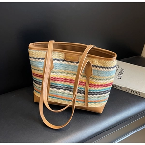 Detail of colorful striped woven tote bag with brown leather handles and brand patch