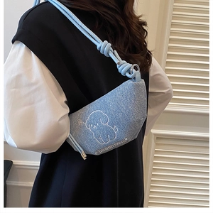 Détail du sac à bandoulière en denim bleu clair avec broderie chien et sangle nouée