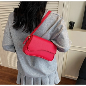 Detail view of red lychee textured shoulder bag with gold-tone hardware on model